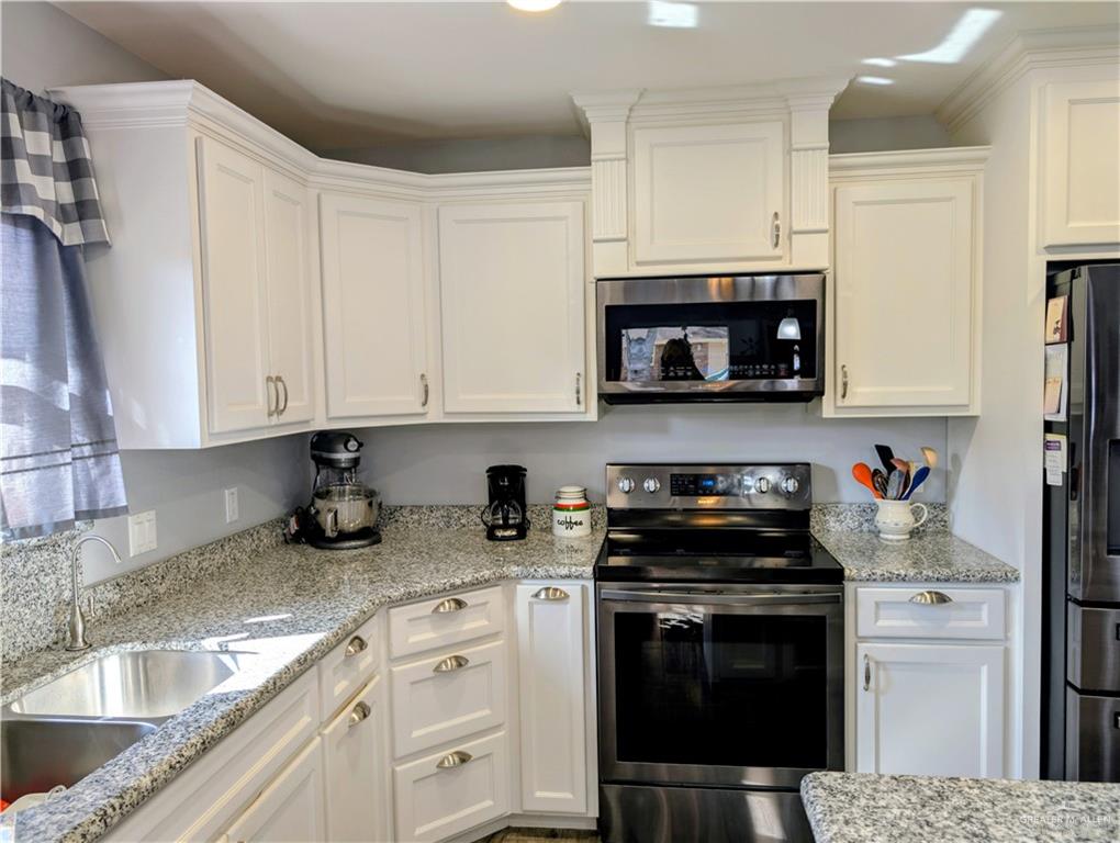 404 Jupiter Street Mission, TX 78572 - Photo 8 of 22 Kitchen featuring appliances with dark stainless steel finishes, white cabinetry, and light stone countertops.
