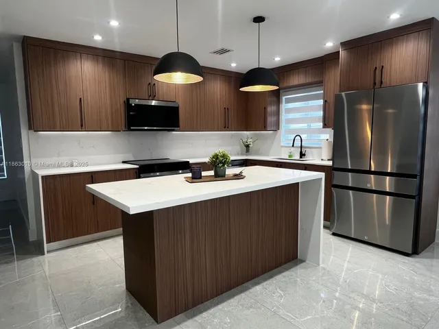 a kitchen with stainless steel appliances a sink a stove a refrigerator and island
