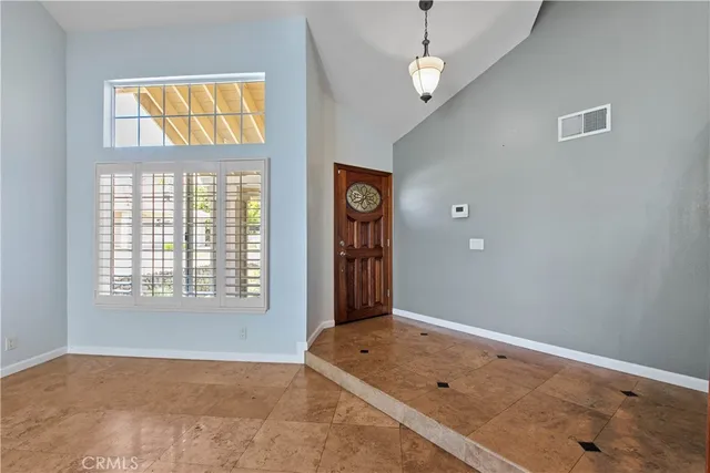 an empty room with wooden floor chandelier and windows