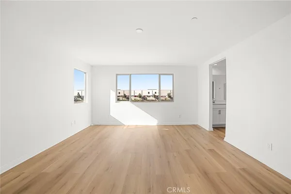 a view of an empty room with wooden floor and closet