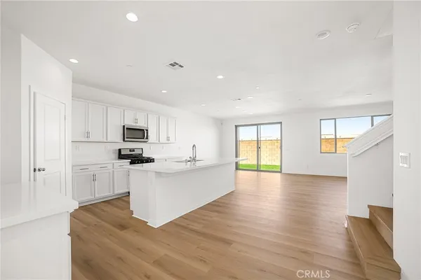 a large white kitchen with cabinets and wooden floor