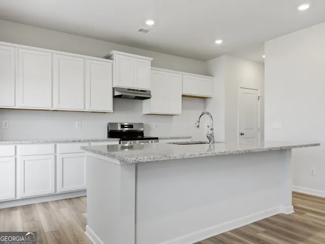 a kitchen with stainless steel appliances granite countertop white cabinets and a stove