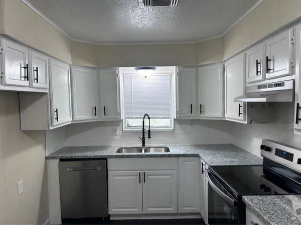 a kitchen with stainless steel appliances granite countertop a sink stove and cabinets