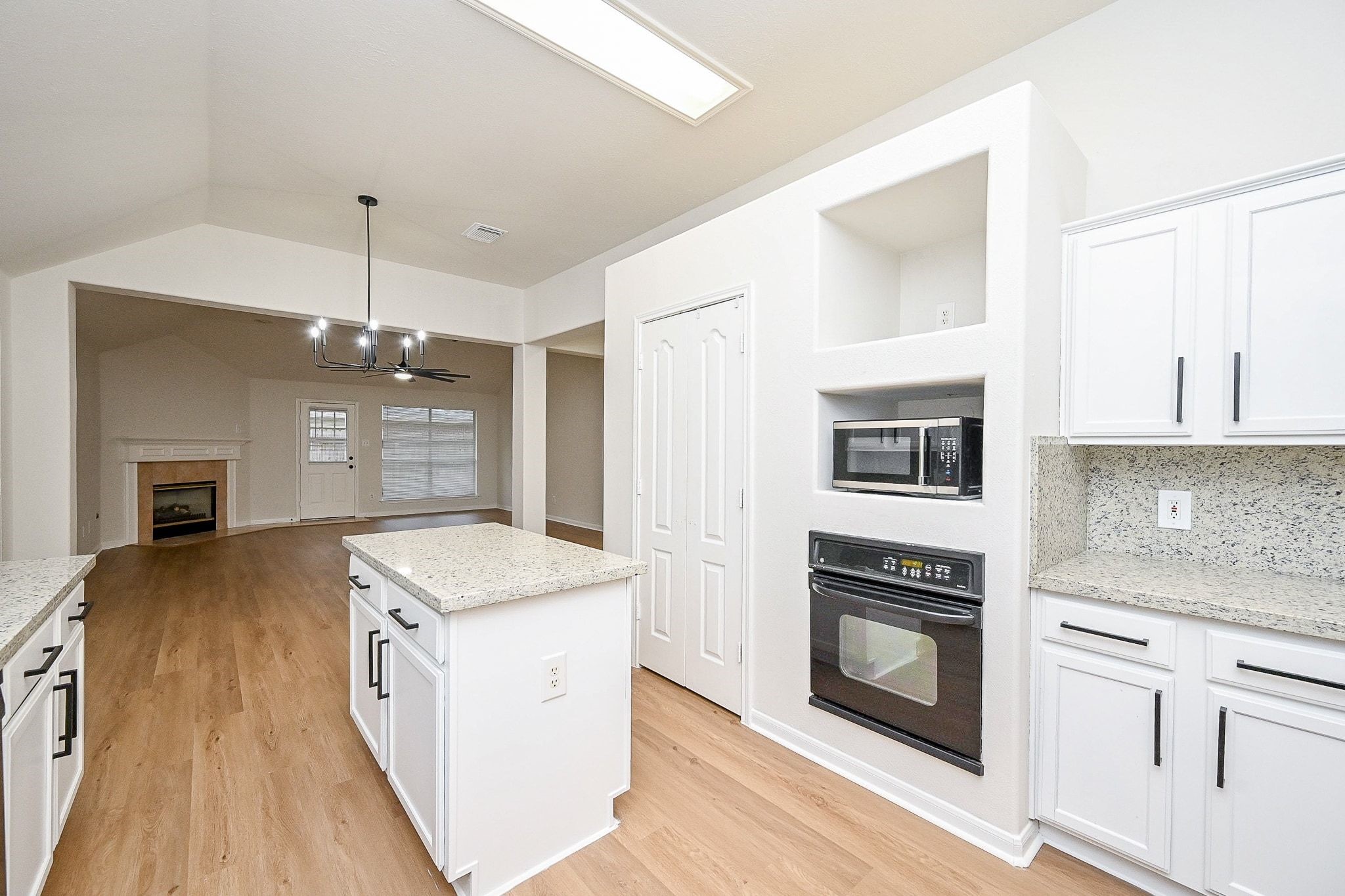 13007 Turnbridge Trail Houston, TX 77065 - Photo 16 of 20 a kitchen with granite countertop a stove top oven a sink dishwasher and a fireplace with wooden floor