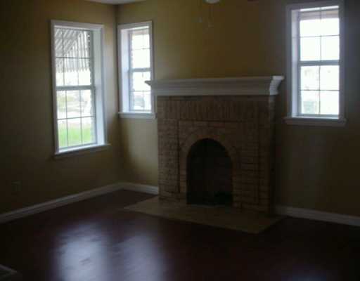 449 Southern Street Corpus Christi, TX 78404 - Photo 2 of 10 an empty room with wooden floor fireplace and windows