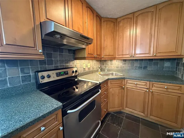a kitchen with granite countertop a sink a stove and cabinets