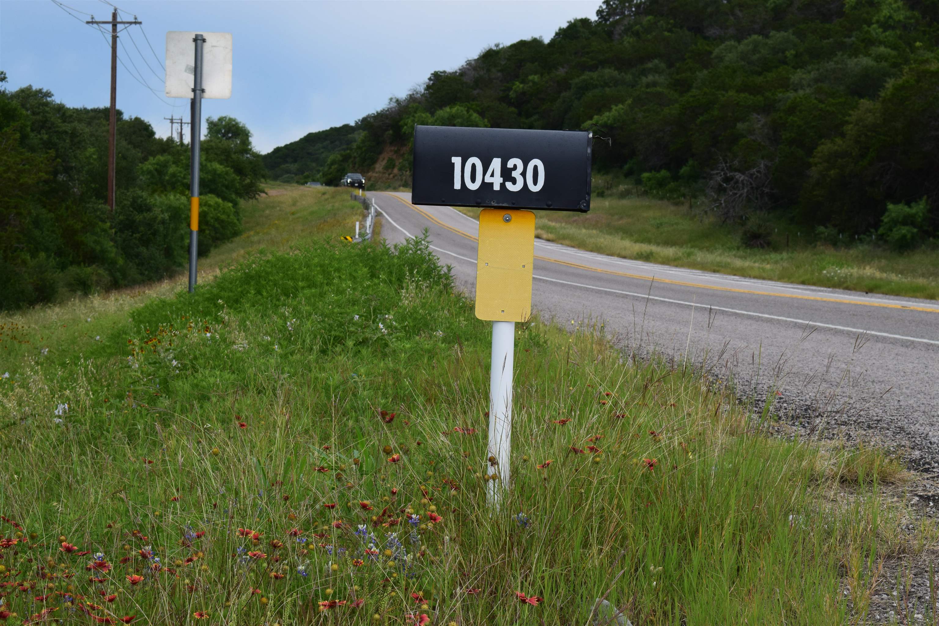 10430 Ranch Road 2341 Burnet, TX 78611 - Photo 10 of 11 a blue sign that is sitting in the grass next to a road