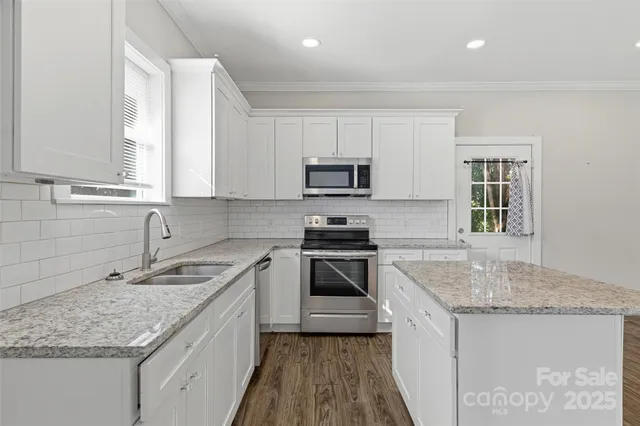 a kitchen with granite countertop a sink stove and cabinets
