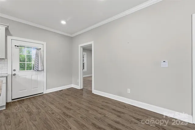 an empty room with wooden floor & windows