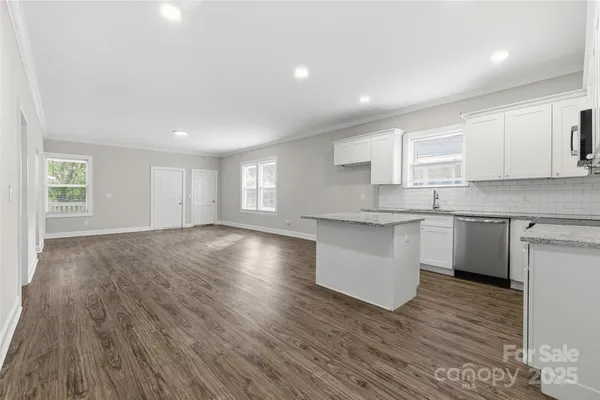 a kitchen with granite countertop a sink cabinets and wooden floor