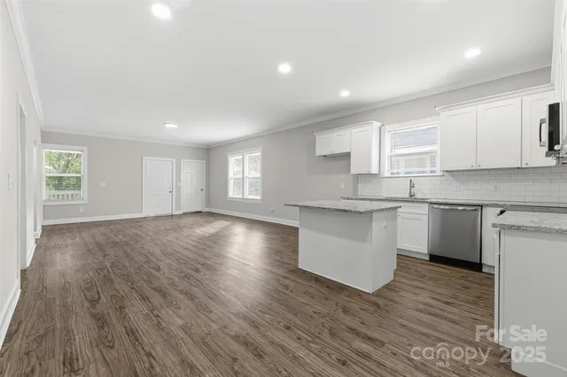 a kitchen with granite countertop a sink cabinets and wooden floor