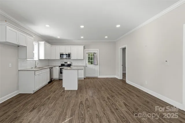 a kitchen with a white wooden cabinets and wooden floor