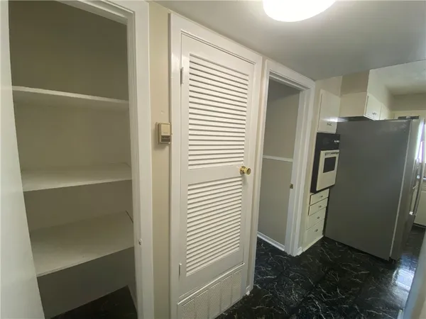 a view of a refrigerator in kitchen and an empty room