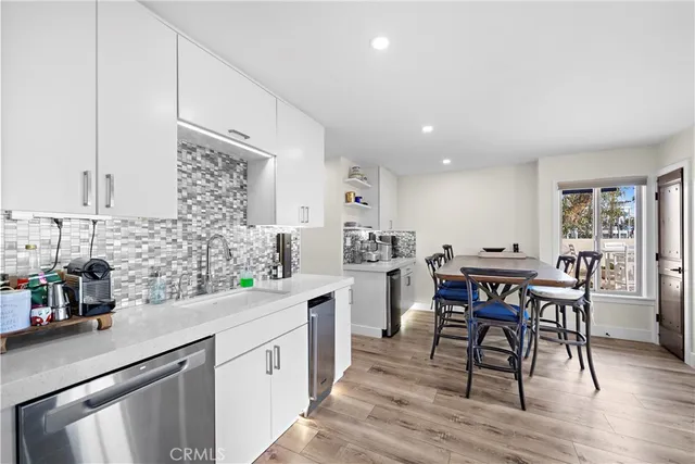 a kitchen with white cabinets sink dining table and chairs