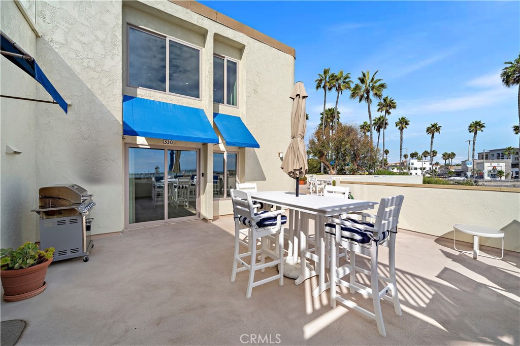 711 Pacific Coast Highway, Unit 330 Huntington Beach, CA 92648 - Photo 9 of 54 a view of a patio with dining table and chairs under an umbrella with potted plants