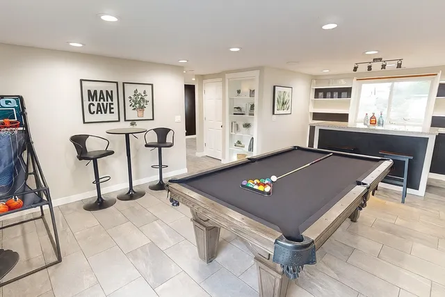a living room with furniture pool table and window