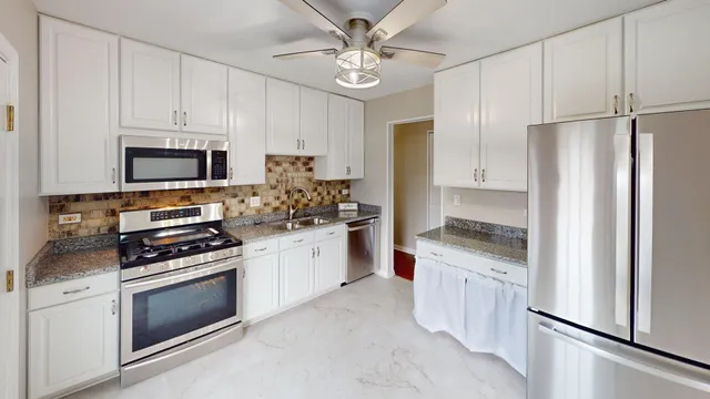 a kitchen with granite countertop a stove sink and refrigerator