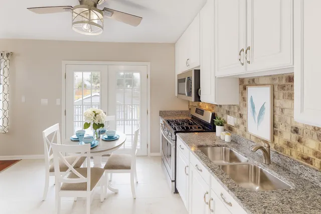 a kitchen with stainless steel appliances granite countertop a sink a stove a dining table and chairs with wooden floor