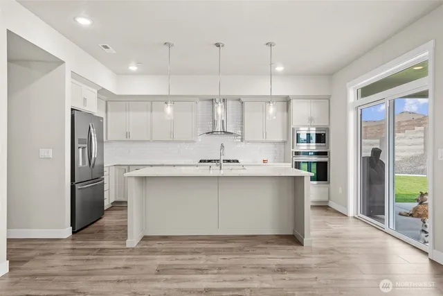 a kitchen with stainless steel appliances granite countertop a refrigerator a sink a stove and a wooden floors