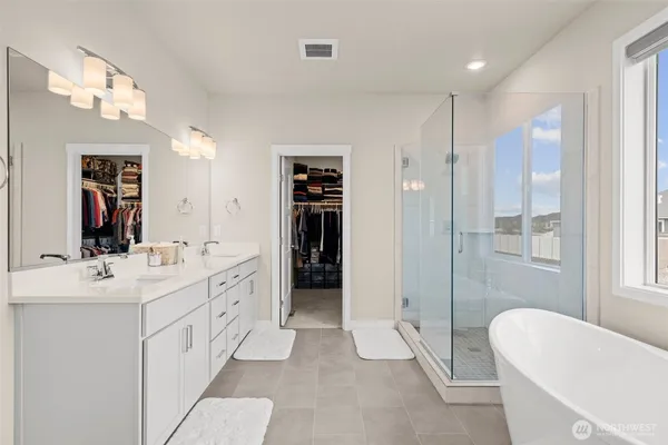 a spacious bathroom with a double vanity sink a large mirror a shower and bathtub