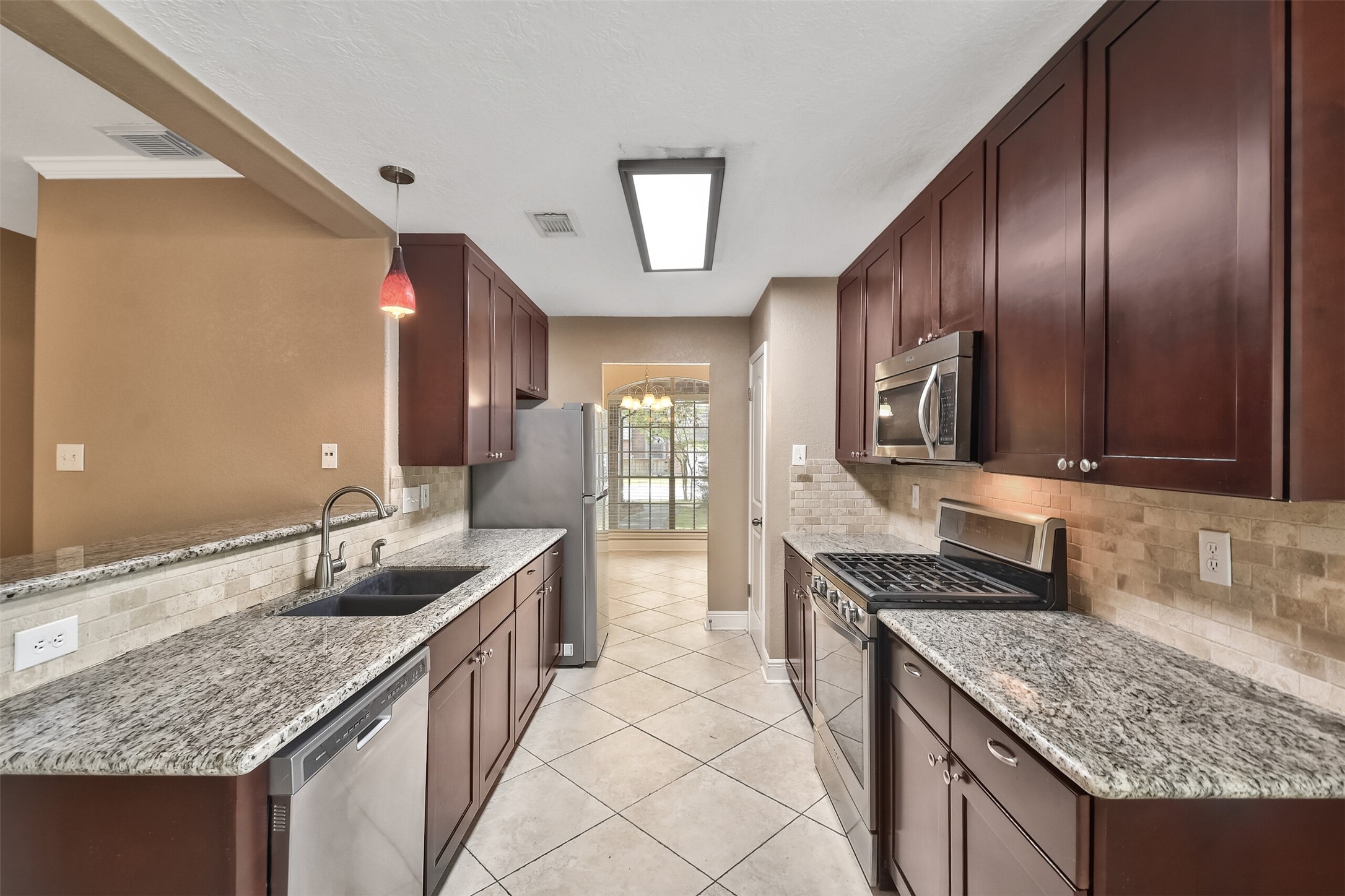 5 East Willowwood Court Spring, TX 77381 - Photo 11 of 27 a kitchen with granite countertop stainless steel appliances a sink stove and cabinets