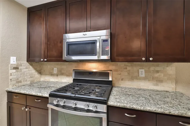 a kitchen with granite countertop a stove and a microwave