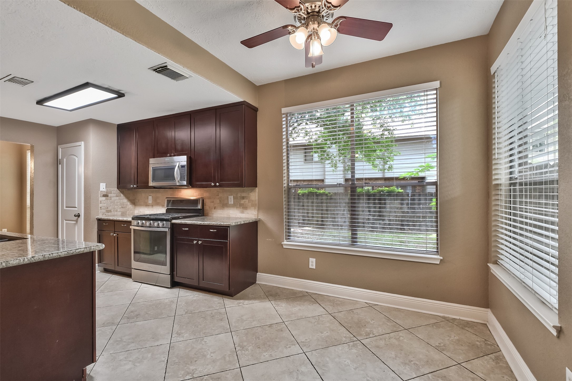 5 East Willowwood Court Spring, TX 77381 - Photo 7 of 27 a large kitchen with kitchen island granite countertop a stove top oven a sink a counter space and cabinets