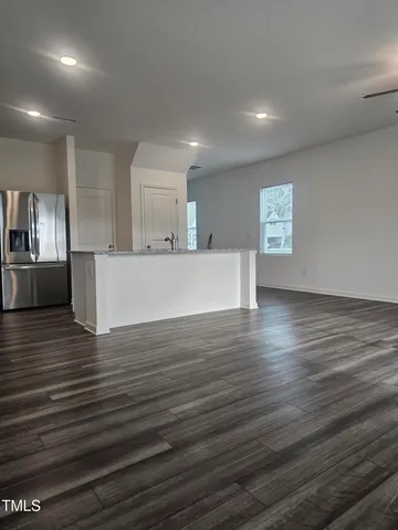 an empty room with wooden floor fan and window