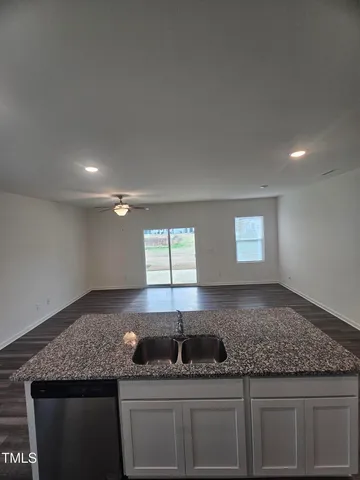 an empty room with wooden floor chandelier fan and windows