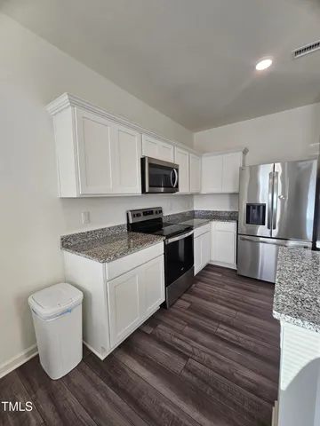 a kitchen with granite countertop a refrigerator stove and sink