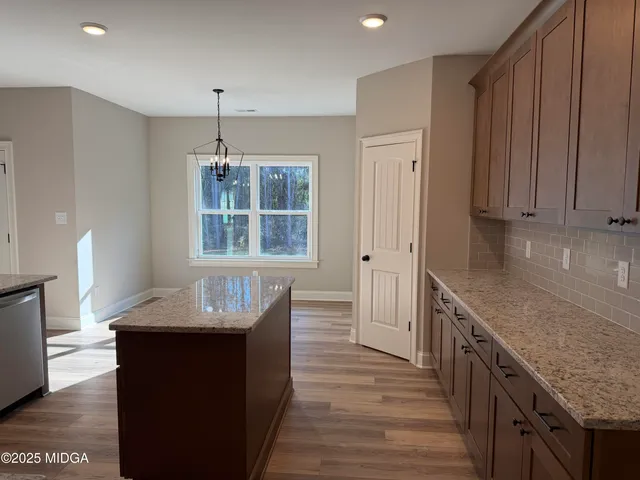 a kitchen with granite countertop kitchen island wooden floors cabinets and stainless steel appliances