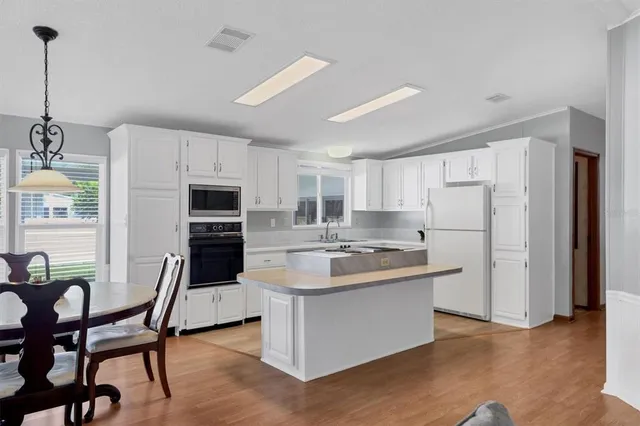 a kitchen with refrigerator a chair and wooden floor