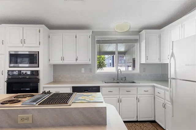 a kitchen with granite countertop a stove a sink and a refrigerator