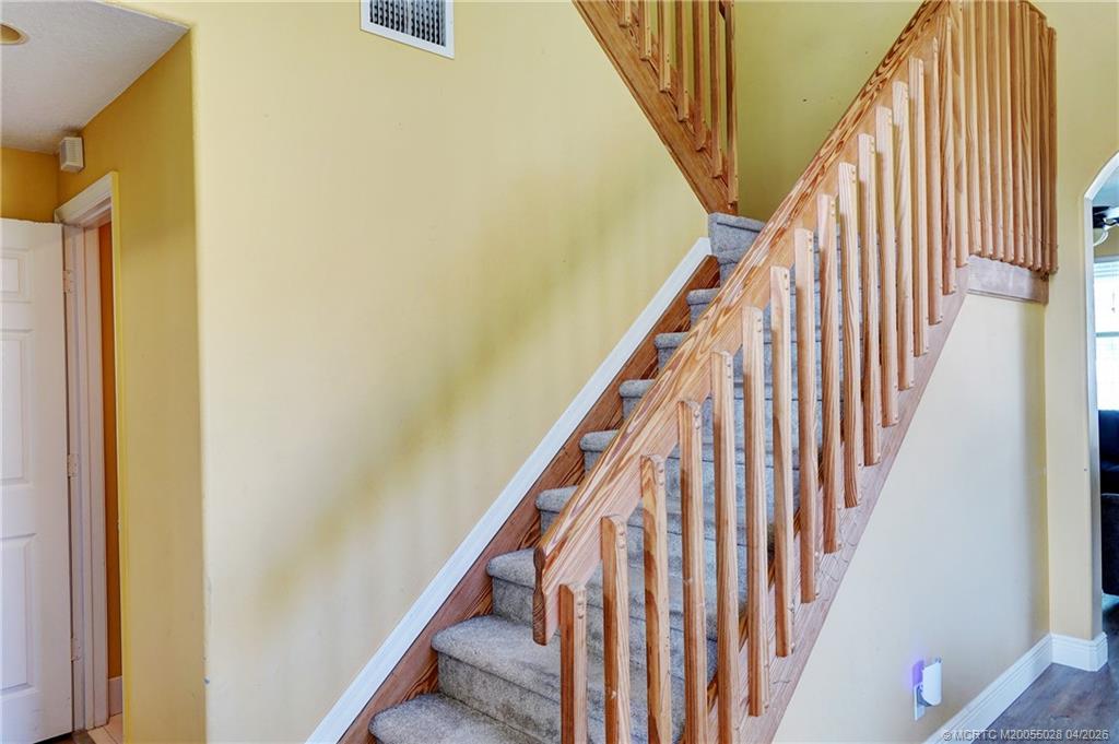2120 Northwest Marsh Rabbit Lane Jensen Beach, FL 34957 - Photo 28 of 34 a view of staircase with wooden floor and white door