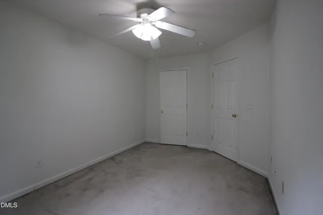 an empty room with a fan & a window