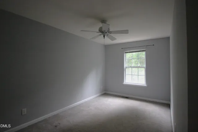 an empty room with a window and a fan