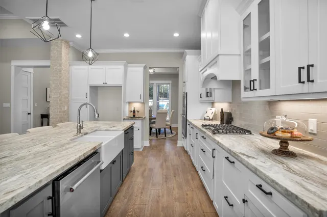 a kitchen with granite countertop a stove a sink a refrigerator and a wooden floor