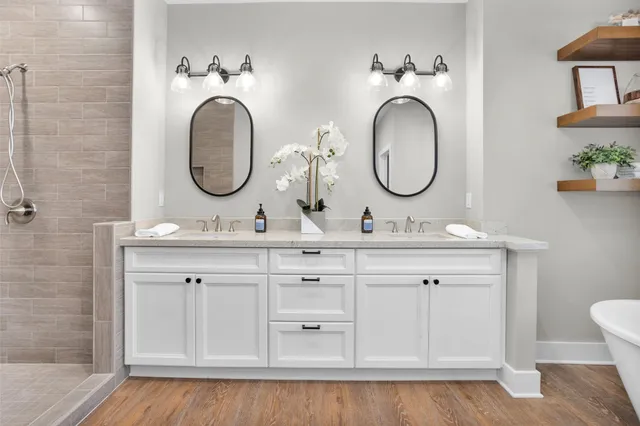 a bathroom with a double vanity sink mirror and bathtub