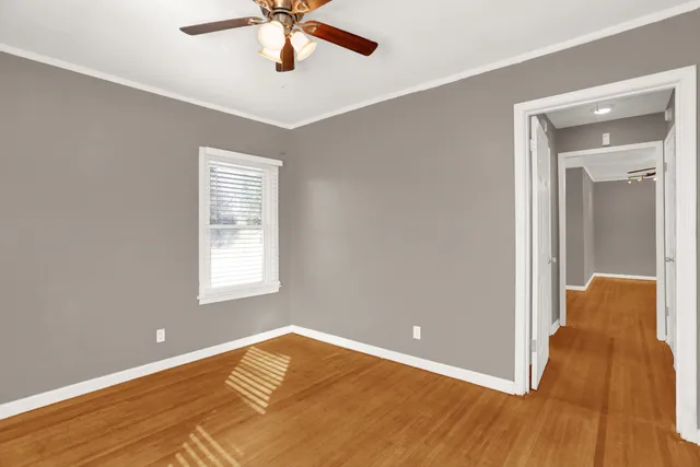a view of an empty room with wooden floor and a window