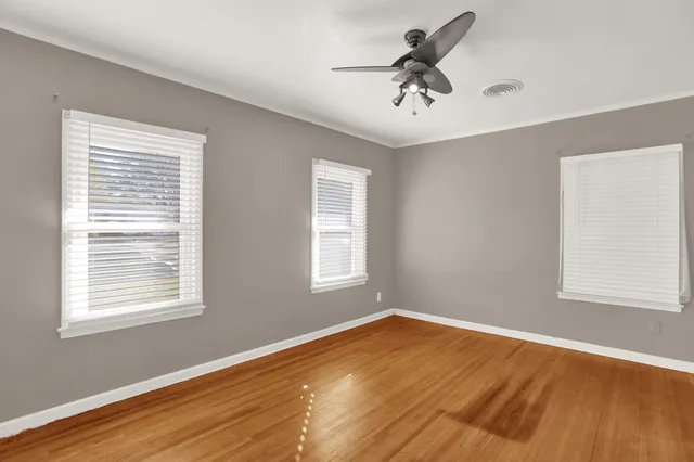 a view of empty room with wooden floor and fan