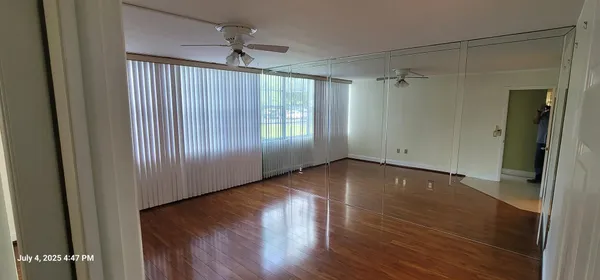 a view of empty room with wooden floor and fan
