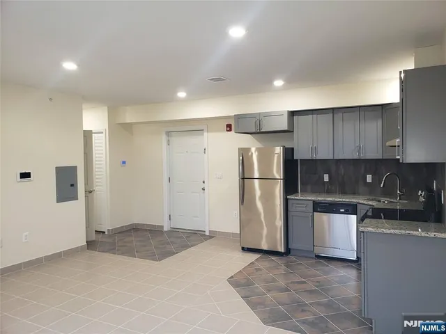 a kitchen with stainless steel appliances granite countertop a refrigerator and a stove top oven