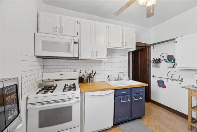 a kitchen with stainless steel appliances granite countertop a refrigerator a stove a sink dishwasher and white countertops with wooden floor