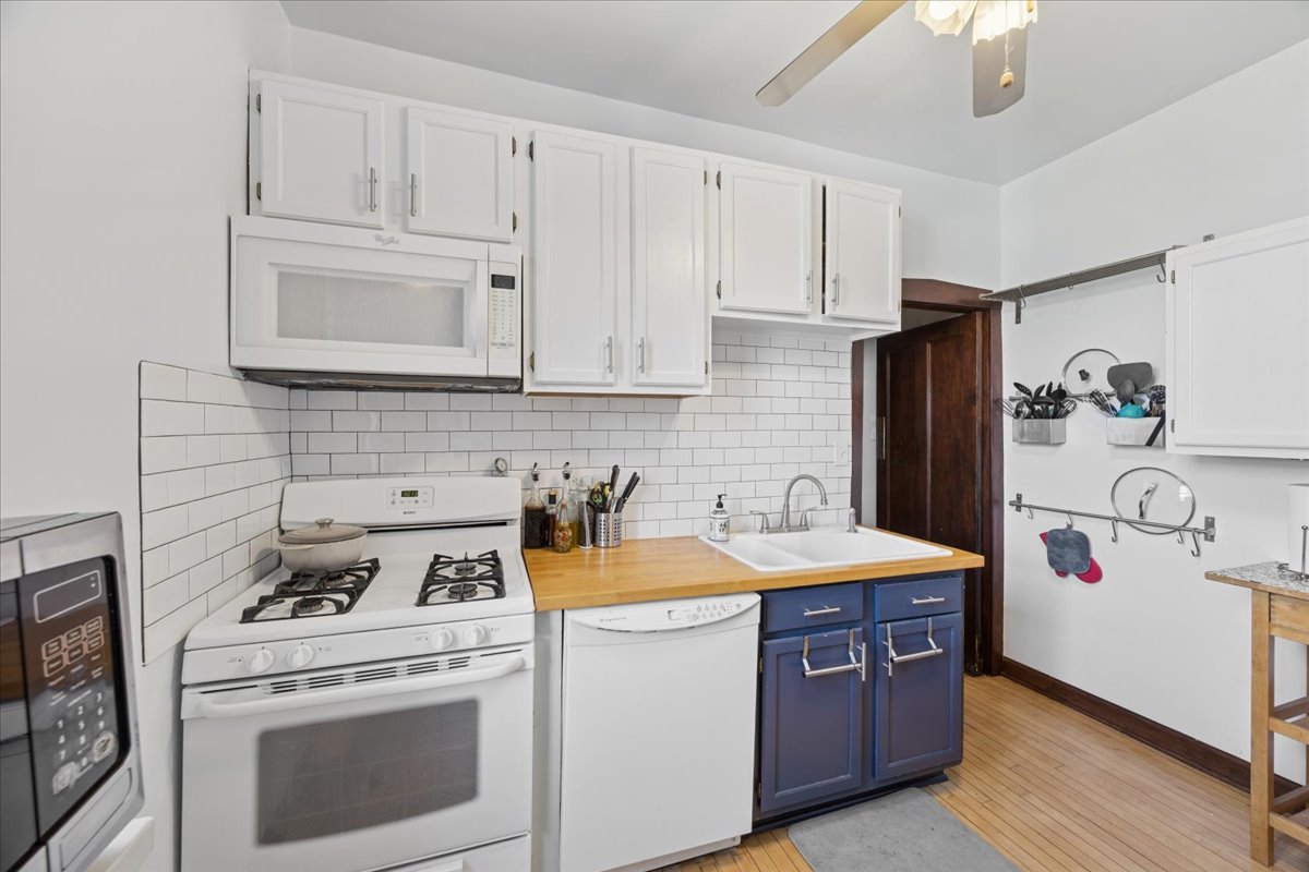 642 Van Buren Street, Unit 2 Oak Park, IL 60304 - Photo 11 of 23 a kitchen with stainless steel appliances granite countertop a refrigerator a stove a sink dishwasher and white countertops with wooden floor
