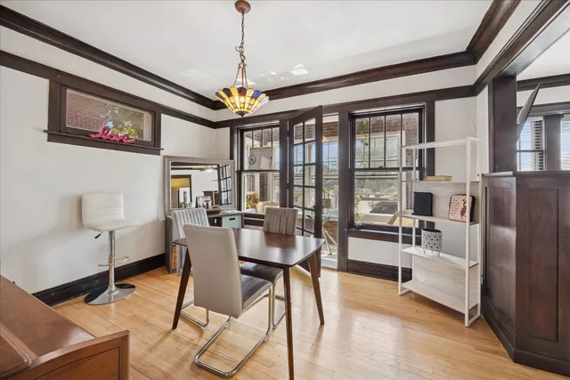 a dining room with wooden floor a chandelier a glass table and chairs