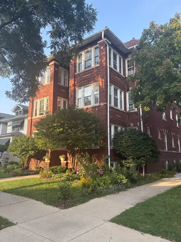 a front view of a house with a garden and trees