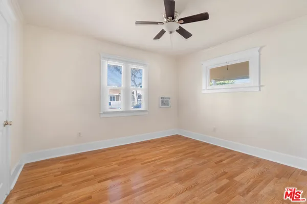 a view of empty room with wooden floor and fan