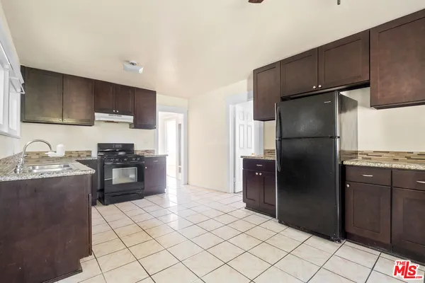a kitchen with granite countertop a refrigerator and a stove top oven