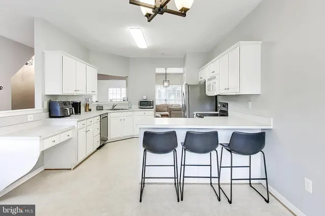 a kitchen with stainless steel appliances granite countertop a stove top oven a sink a dining table and chairs