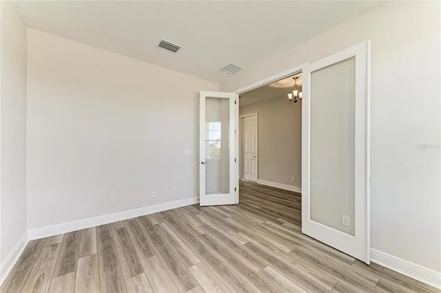 a view of an empty room with wooden floor and a bathroom